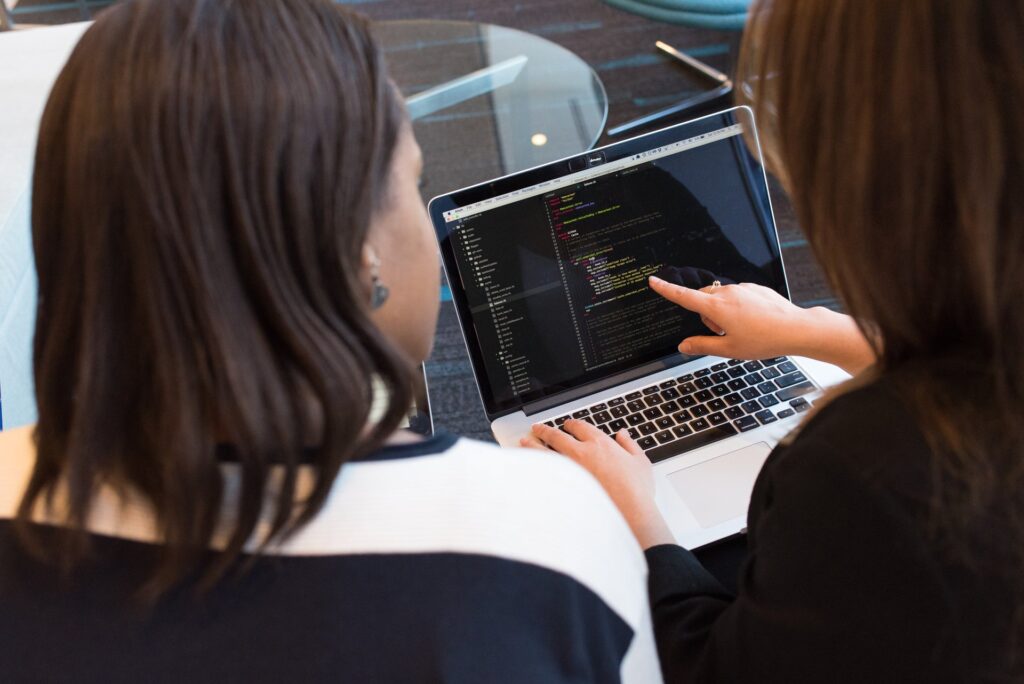 Two developers reviewing code together on a laptop